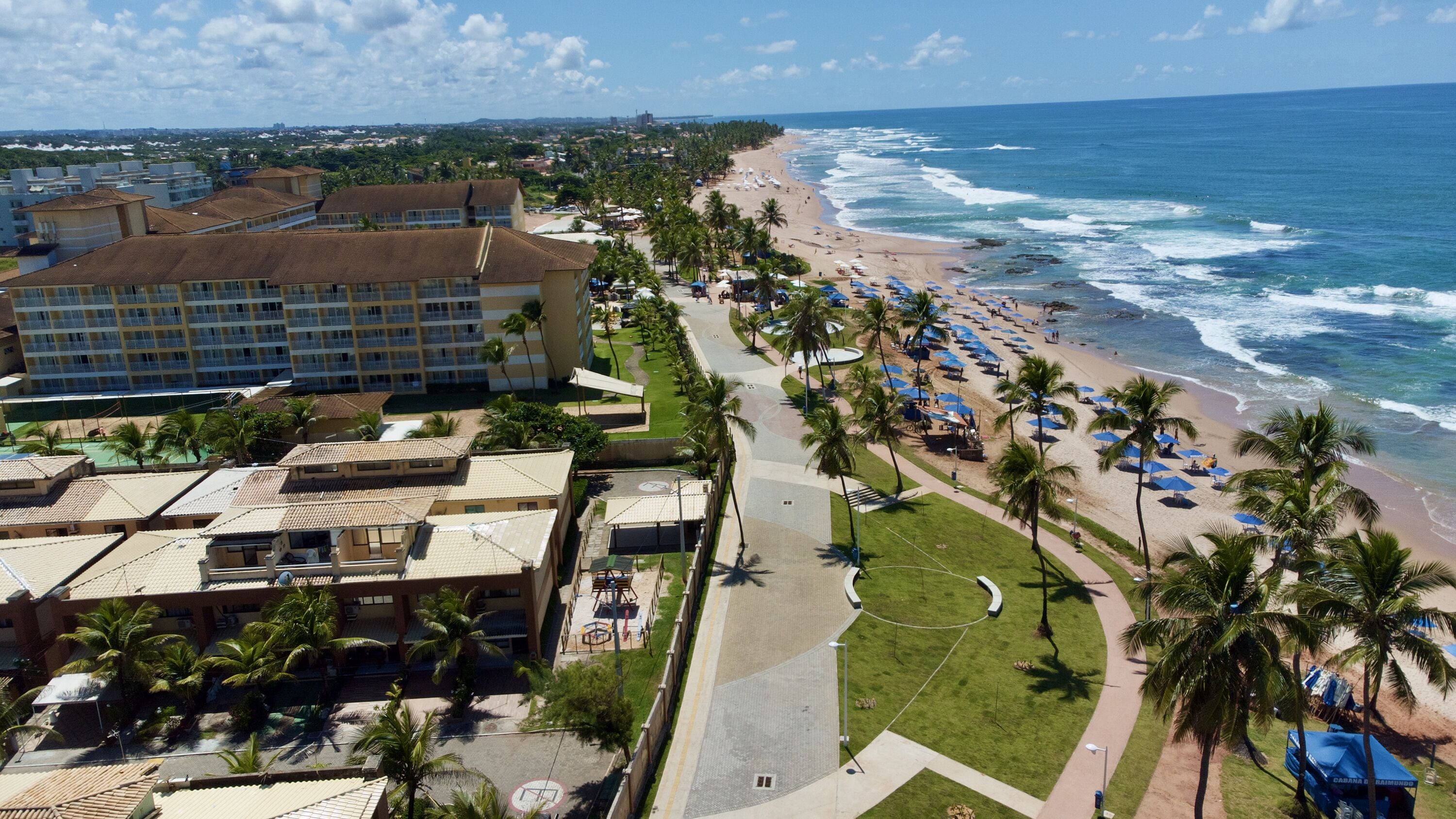 A coastal hotel with a beach view, multiple floors, and a parking area.