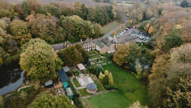 An aerial view of a large estate with multiple buildings, a courtyard, and a parking area.