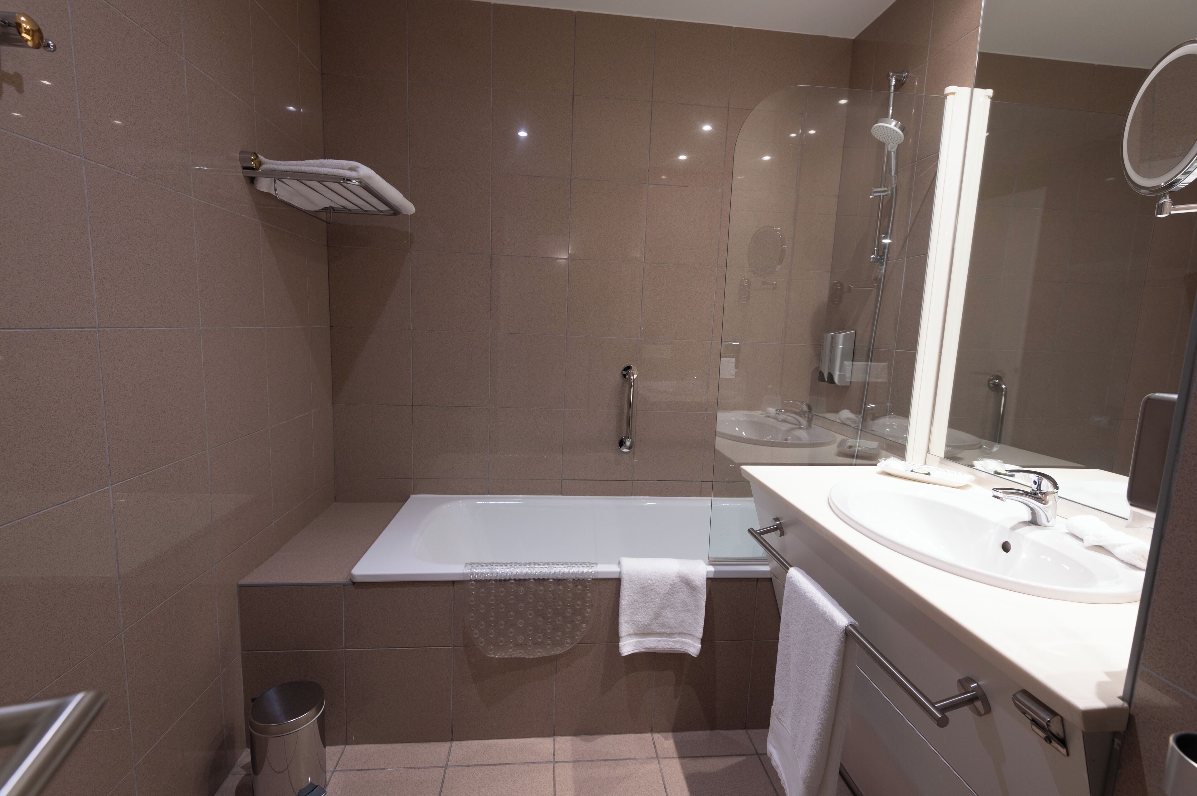 Un baño moderno con bañera, ducha, lavabo y espejo.
