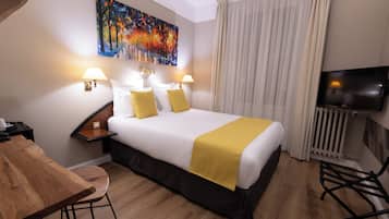 Una habitación de hotel con una cama grande, dos lámparas de noche, un cuadro en la pared, un televisor y un escritorio de madera.