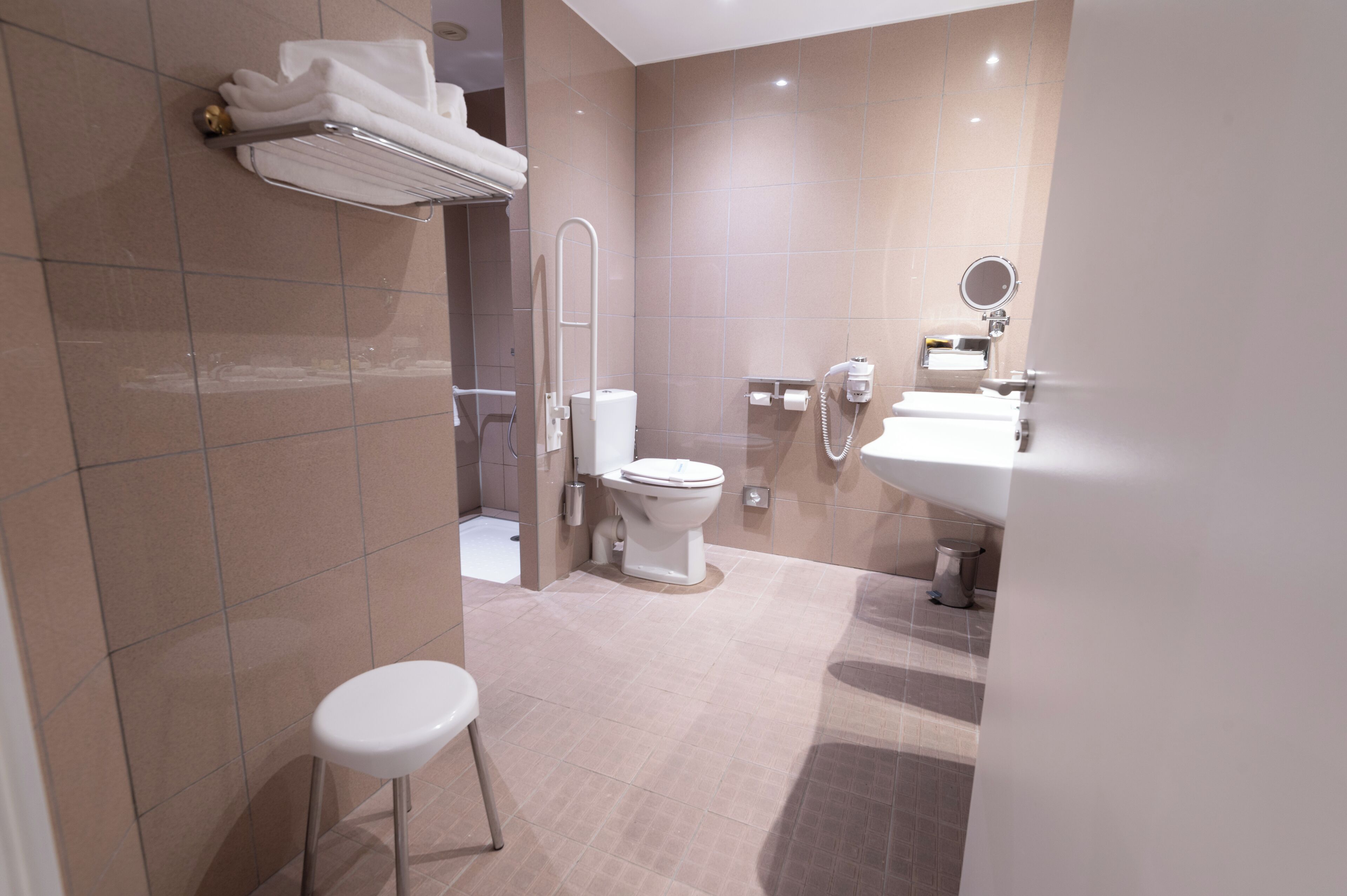 Un baño moderno con inodoro, lavamanos y un pequeño taburete.