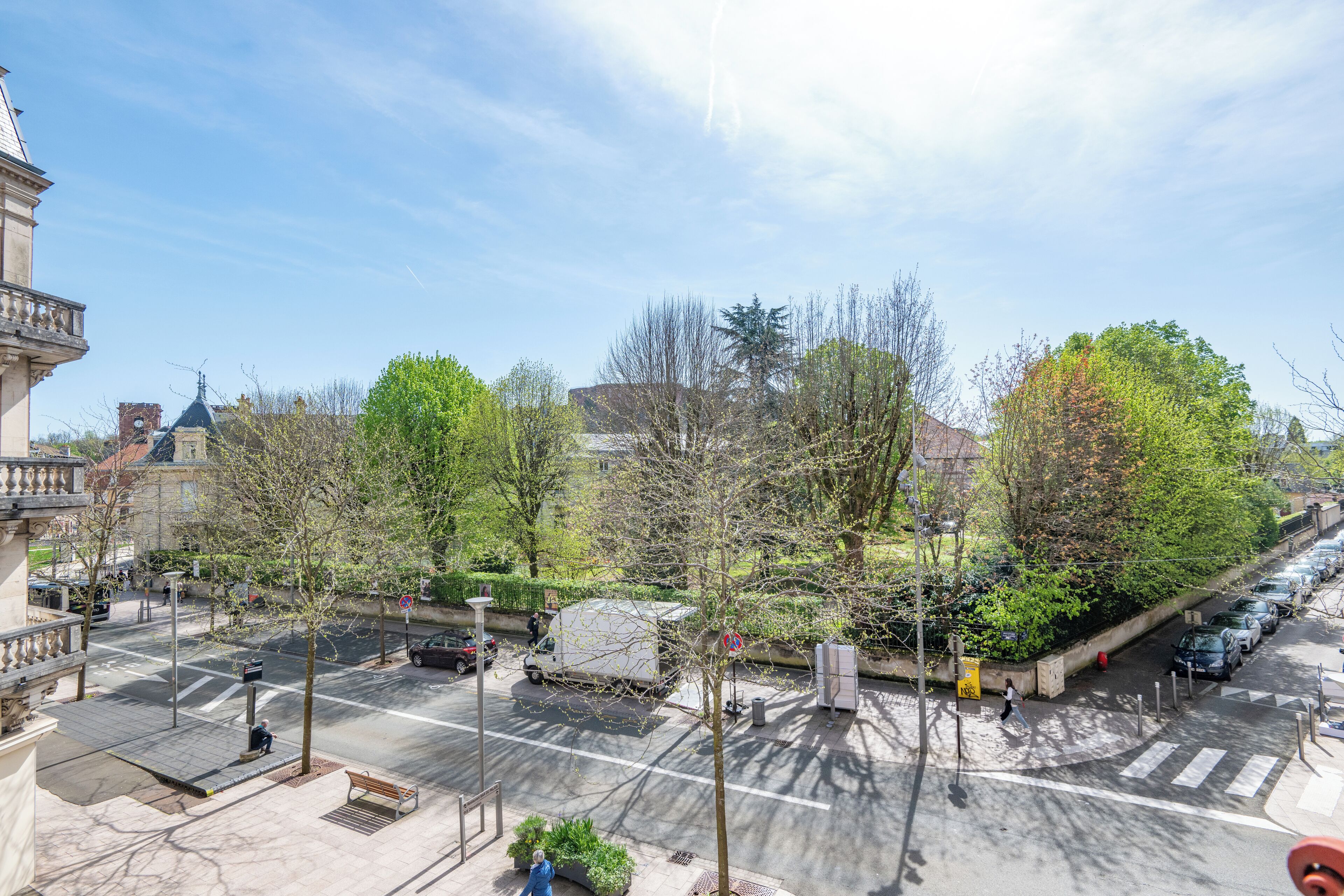 A street view with a crosswalk, trees, and parked cars.