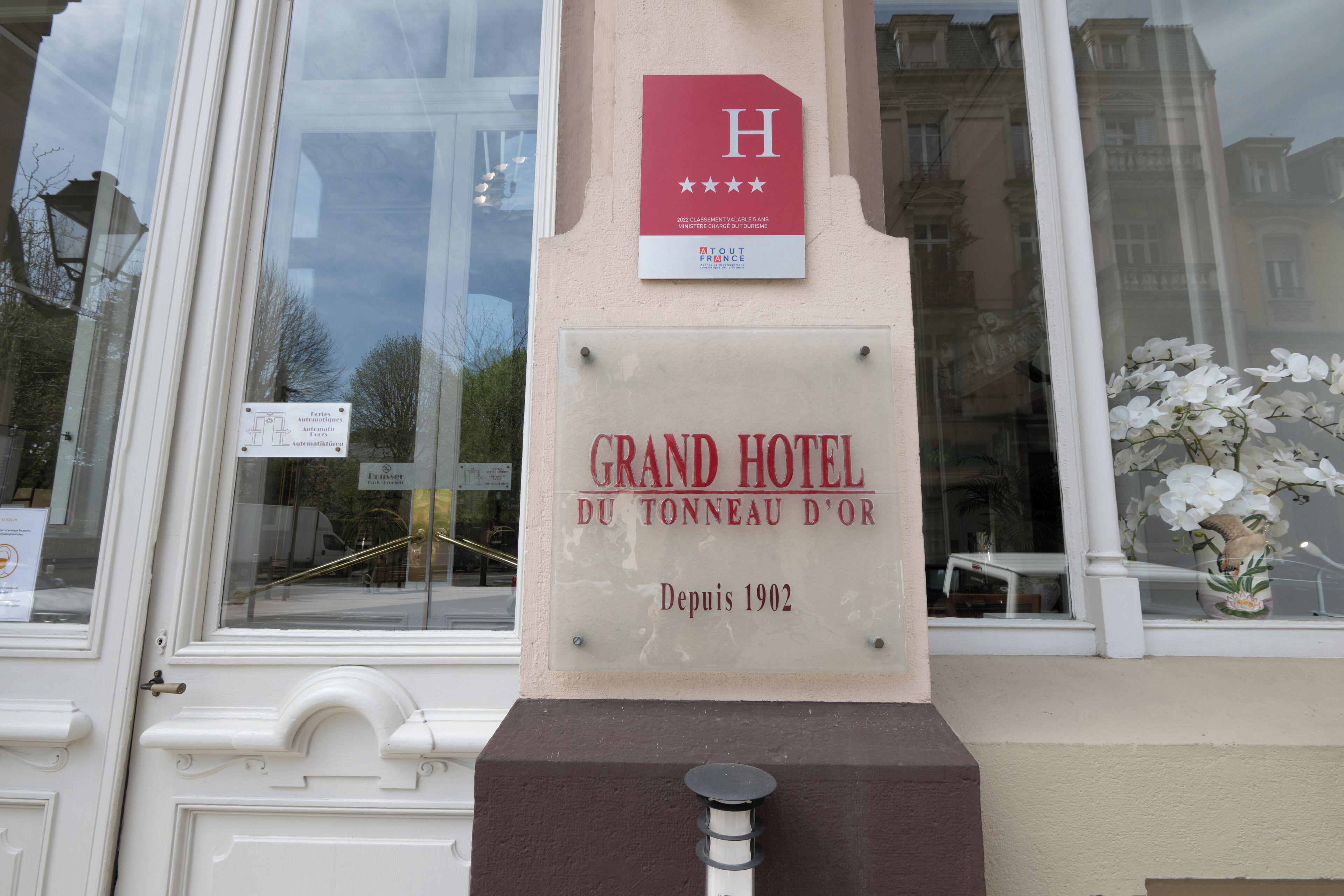Une plaque sur un immeuble portant l’inscription « GRAND HÔTEL DU TONNEAU D’OR » et « Depuis 1902 ».