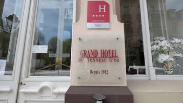 Une plaque sur un immeuble portant l’inscription « GRAND HÔTEL DU TONNEAU D’OR » et « Depuis 1902 ».