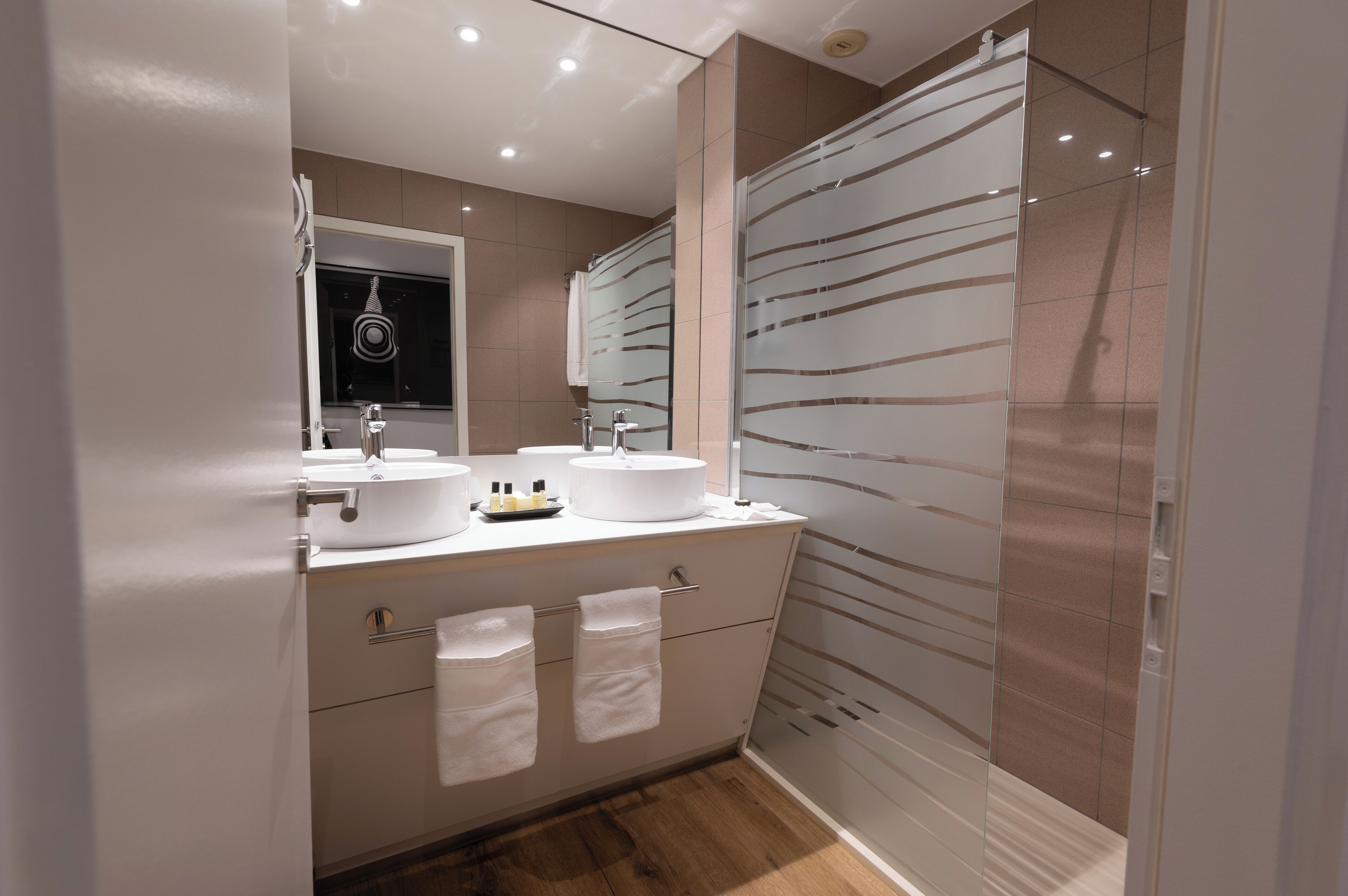 Un baño moderno con dos lavamanos, un espejo y cabina de ducha de vidrio.