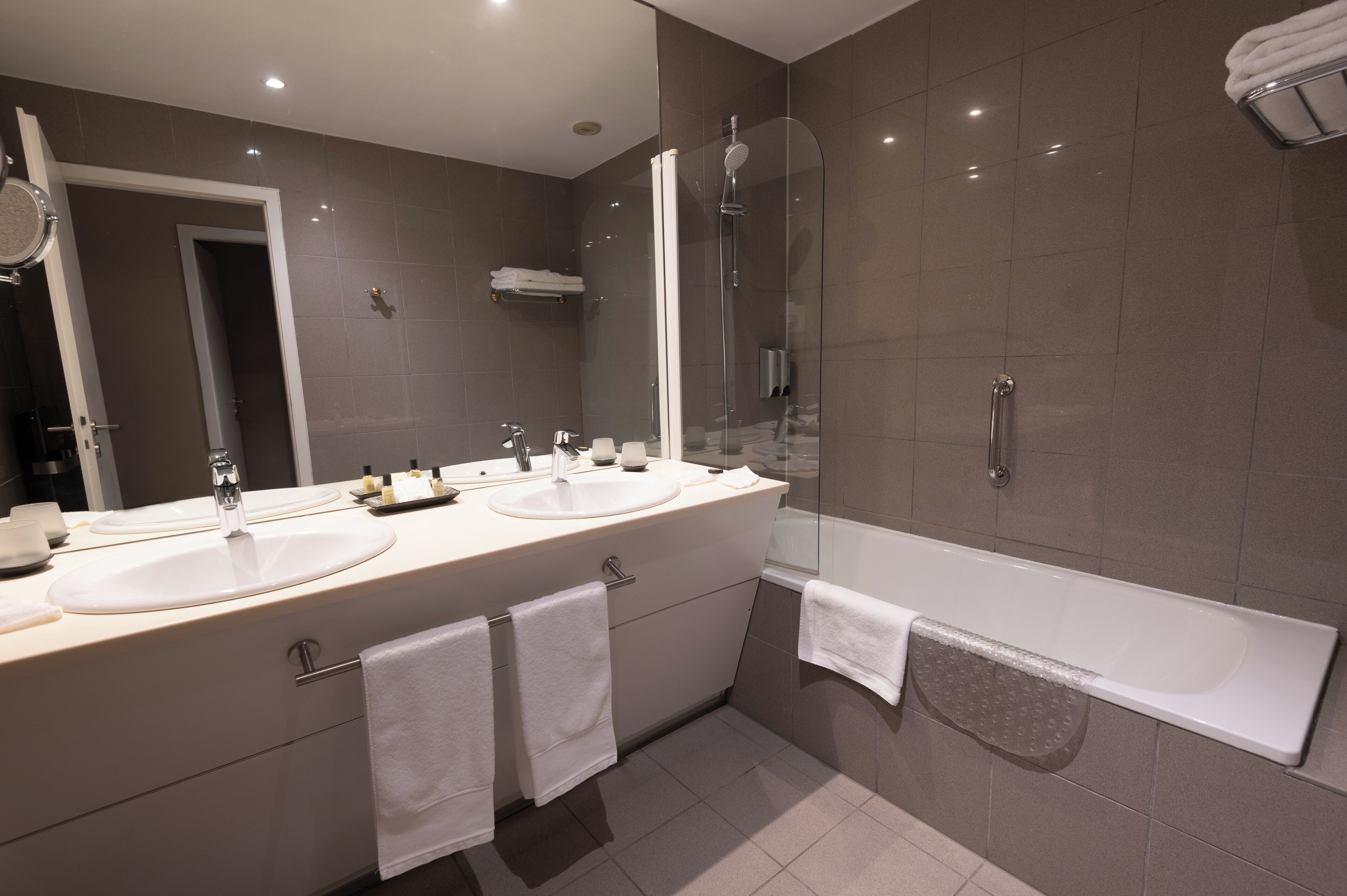 A modern bathroom with two sinks, a glass-enclosed shower, and a bathtub.