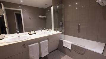 A modern bathroom with two sinks, a glass-enclosed shower, and a bathtub.