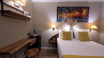 A hotel room with a bed, bedside lamps, a desk, a chair, a painting on the wall, and a shelf with a lamp.