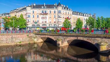 A historic building with multiple stories, a bridge over a canal, and a fence with colorful flowers.