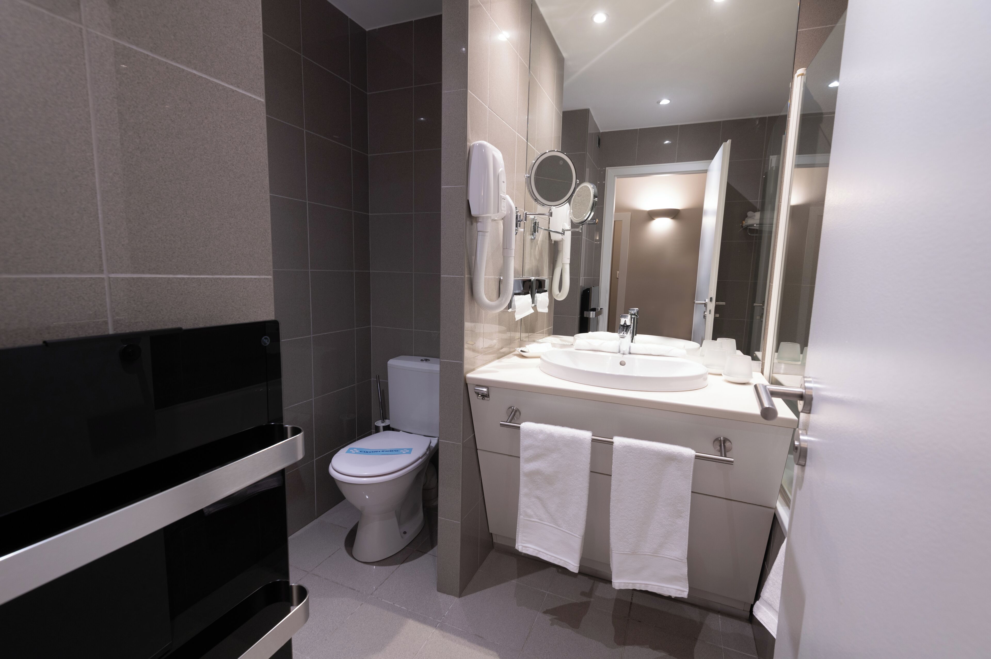A modern bathroom with a toilet, sink, and mirrors.