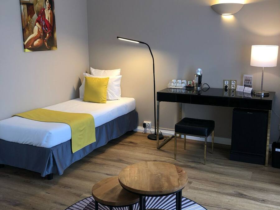 A hotel room with a bed, desk, chair, and a round wooden table.