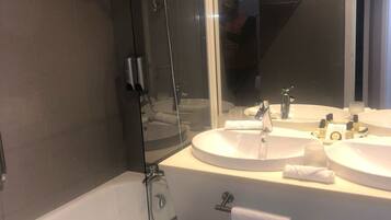 A modern bathroom with a glass-enclosed shower, two sinks, and a large mirror.