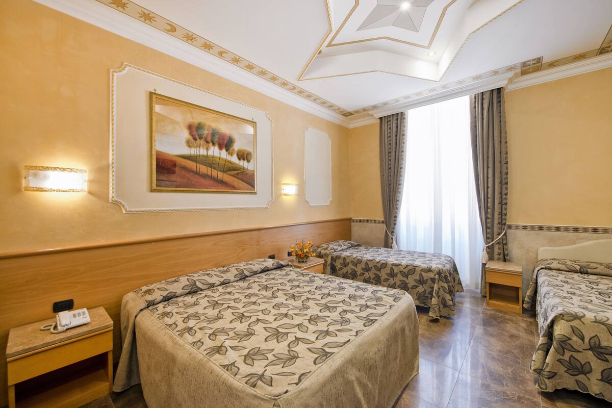 A hotel room with two beds, a painting on the wall, and a nightstand with a phone.