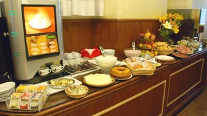 A buffet setup with a coffee machine, various breakfast items, and a vase of flowers. - Hotel Marco Polo (Rome)