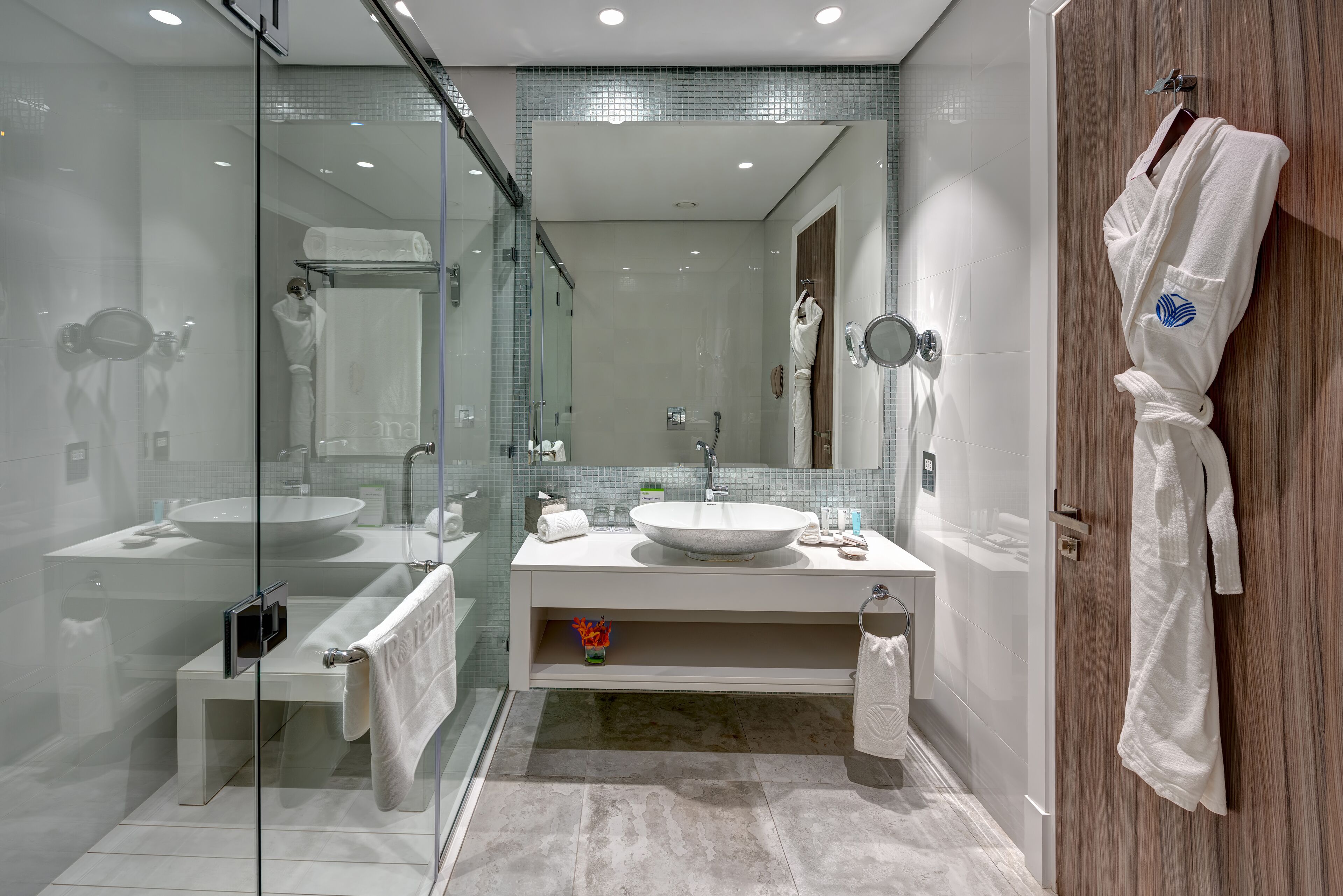 Un baño moderno con ducha de vidrio, un lavamanos grande y un mueble de tocador con espejo.
