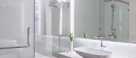 Une salle de bain moderne avec une douche à l’italienne en verre, un lavabo blanc doté d’une grande cuve et un meuble-lavabo en verre.