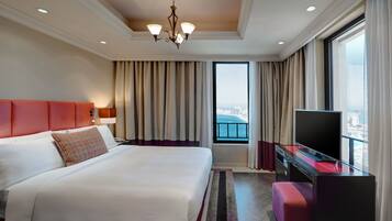 Habitación de hotel con una cama grande, televisión, escritorio y vistas a la ciudad.