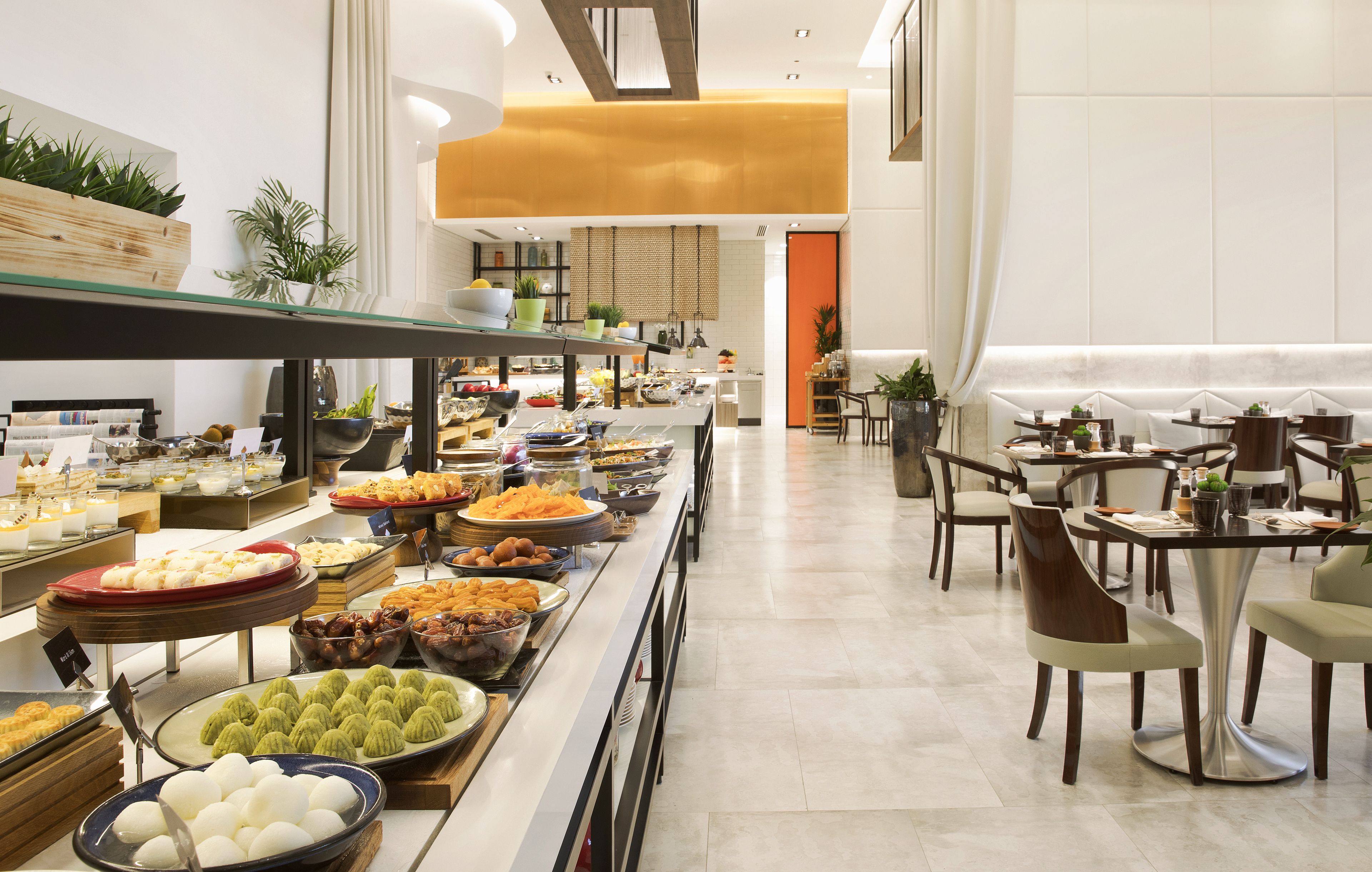Un bufé con diferentes opciones de comida y disposición de mesas.