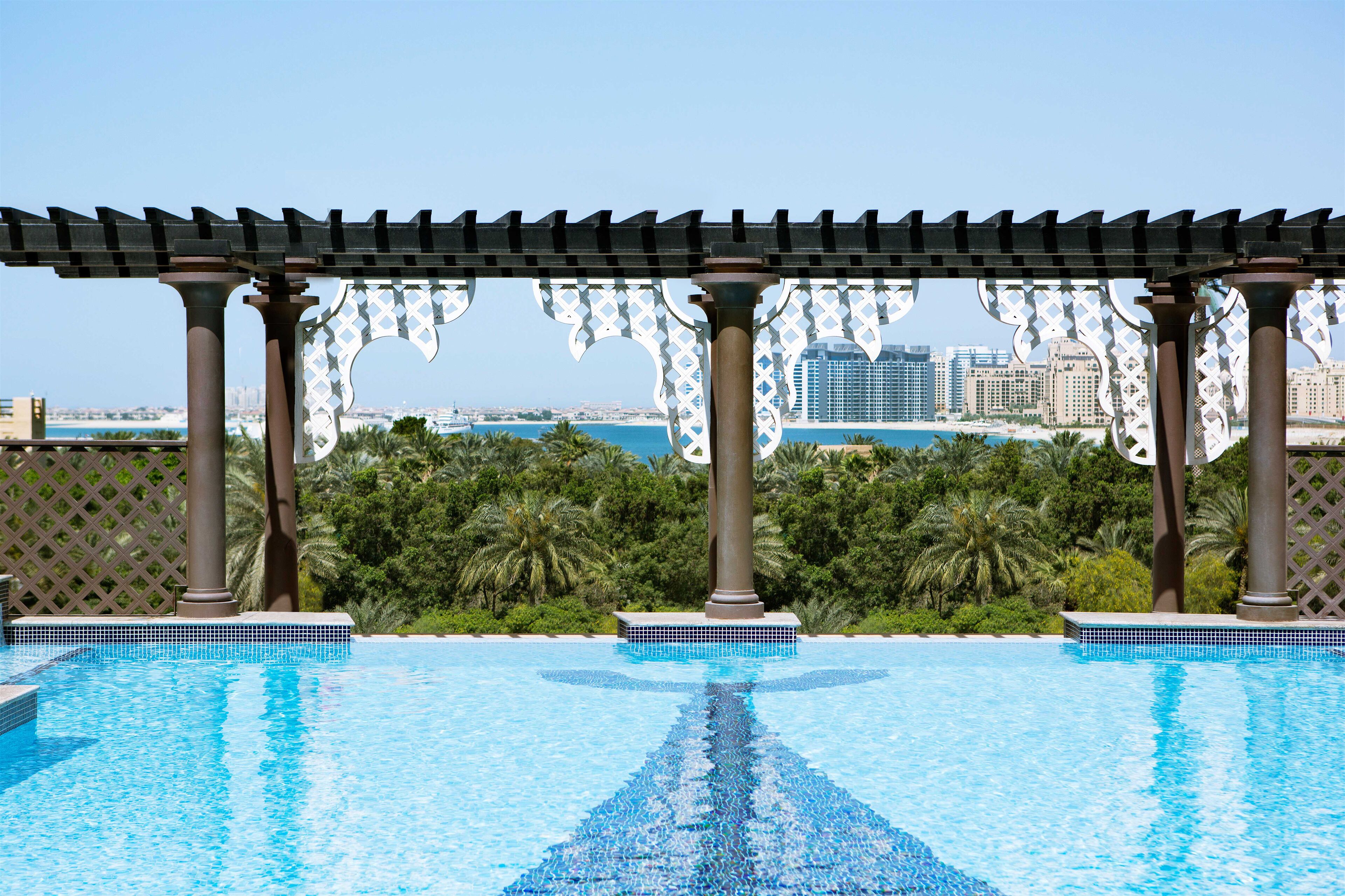 A swimming pool with a view of a cityscape and palm trees.
