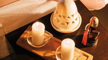 A massage therapy session with candles and a decorative item on a wooden tray.