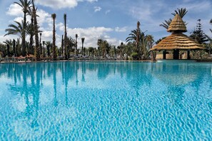 A clear blue pool with lounge chairs and palm trees. - Hotel Riu Tikida Beach - Adults Only - All inclusive (Agadir)