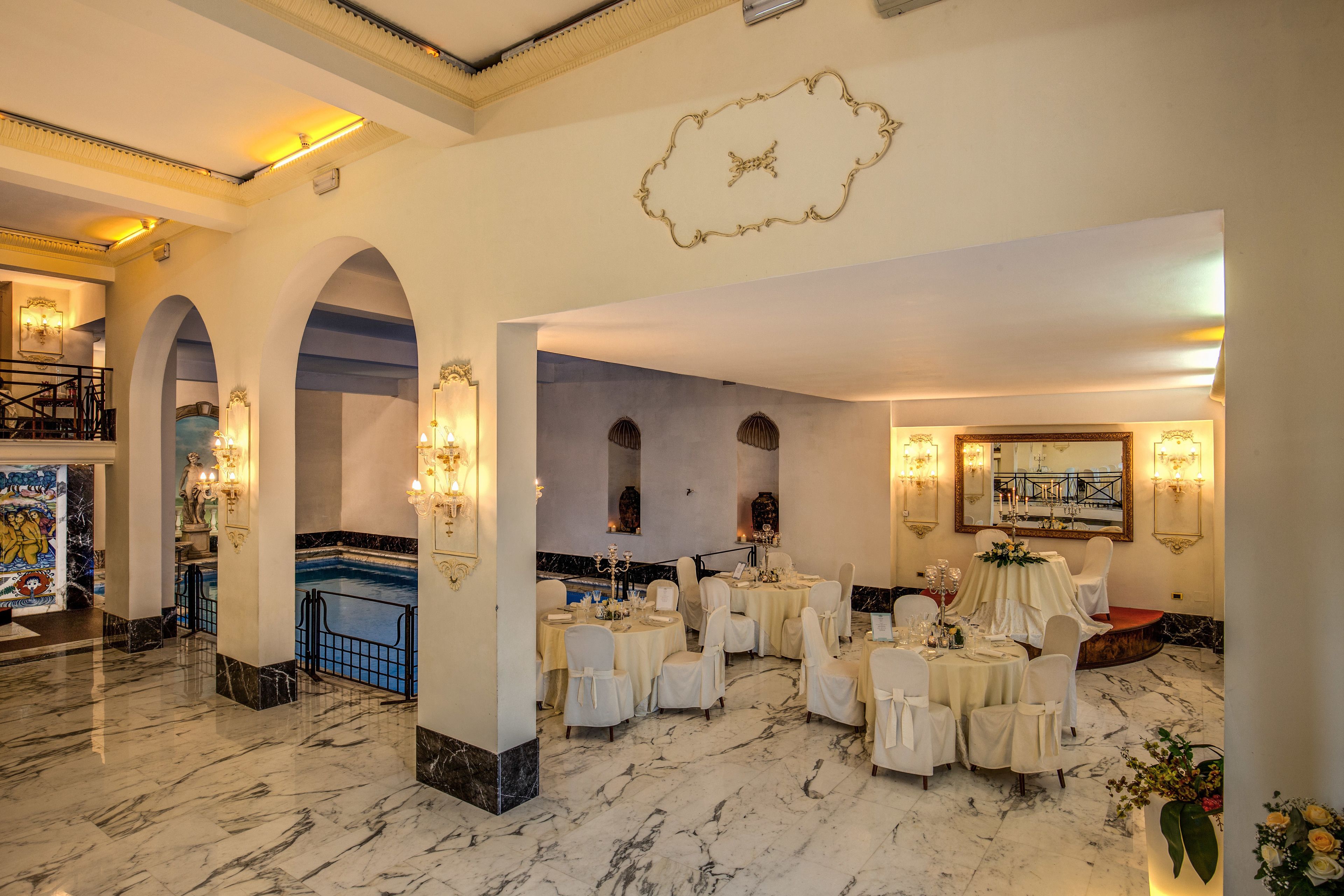 A luxurious hotel lobby with marble floors, elegant chandeliers, and a grand staircase.
