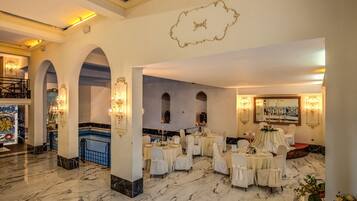 A luxurious hotel lobby with marble floors, elegant chandeliers, and a grand staircase.