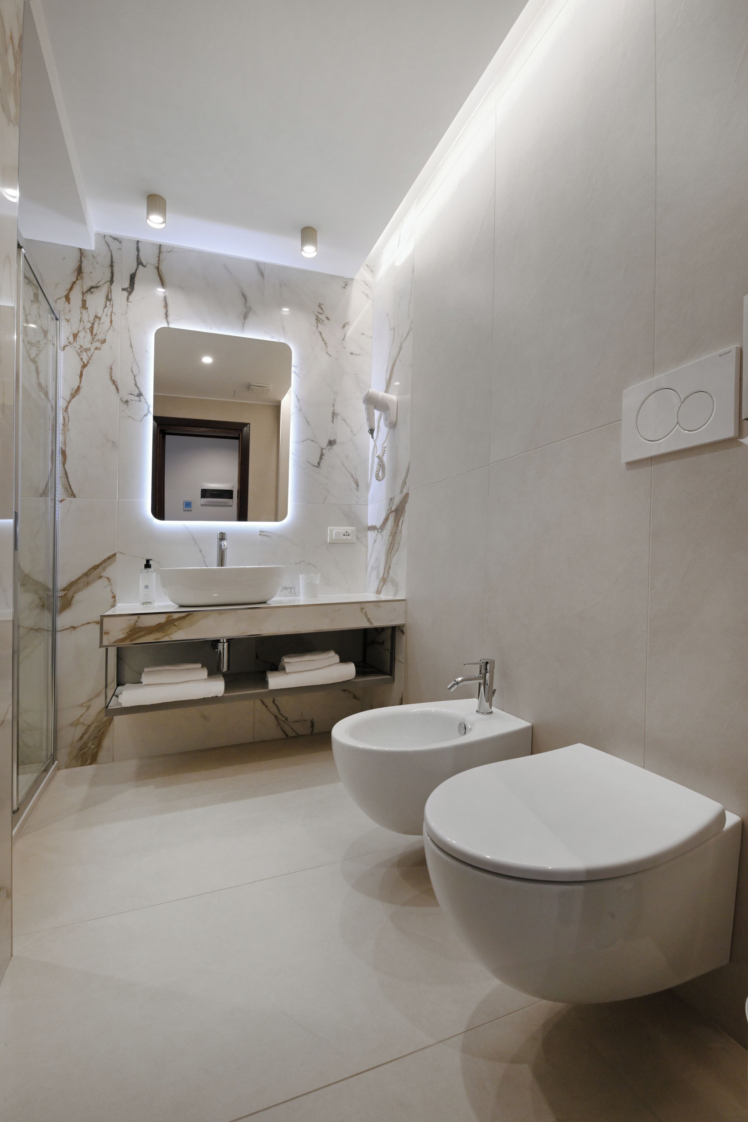 A modern bathroom with two sinks, a large mirror, and a toilet.