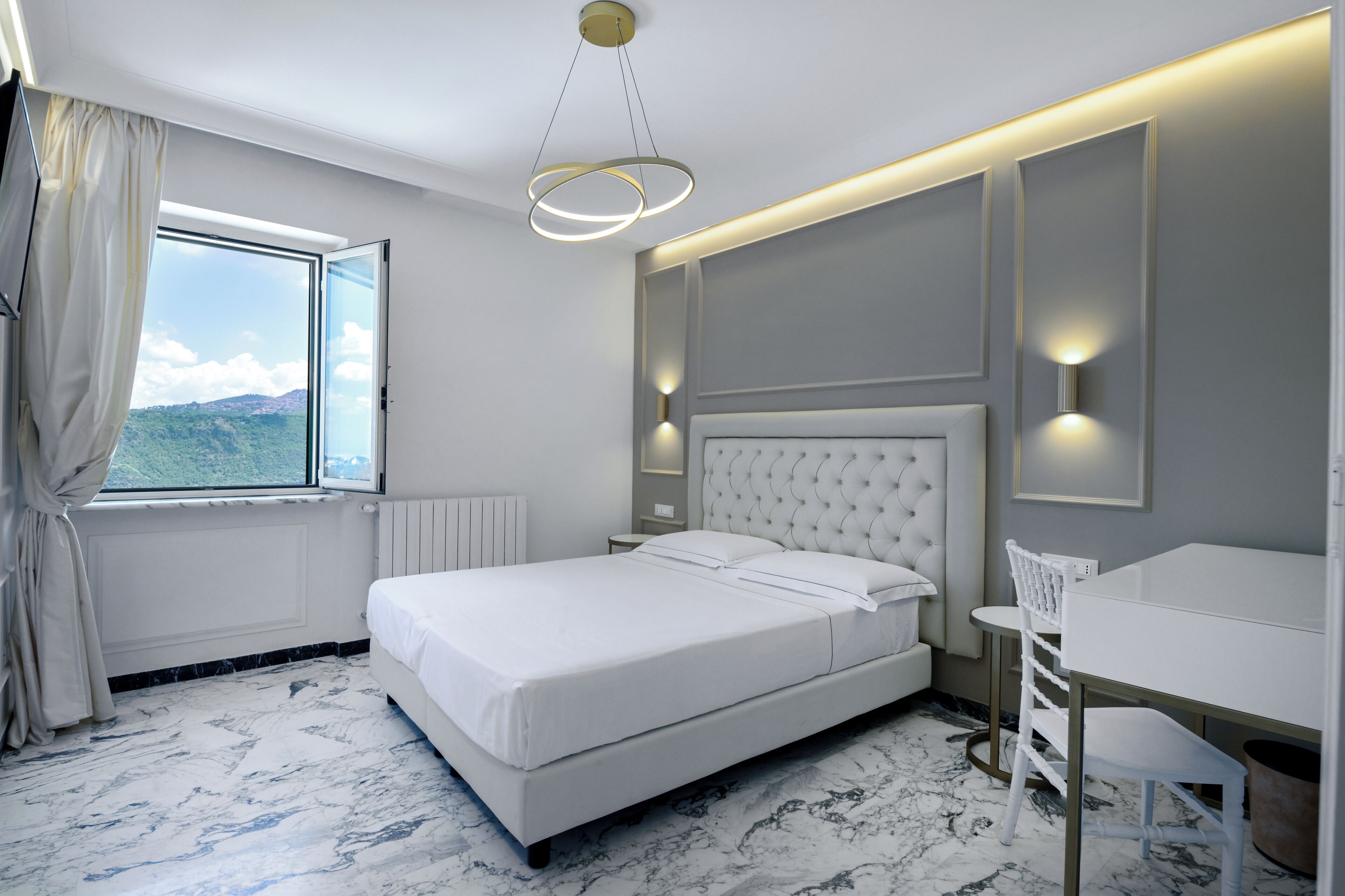 Une chambre moderne avec un grand lit, un bureau et une vue sur l’extérieur.