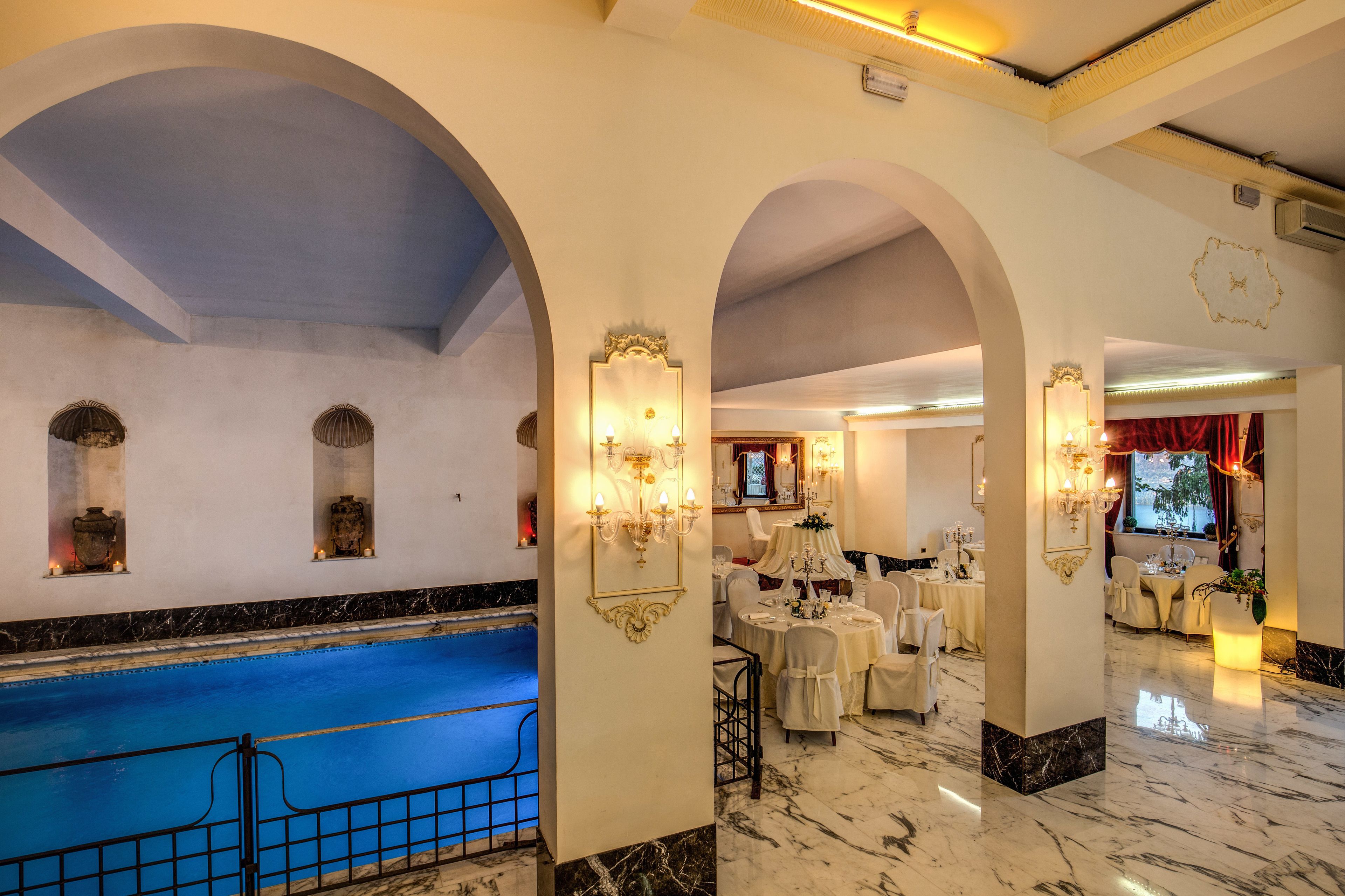 A hotel lobby with a pool, marble flooring, and elegant chandeliers.