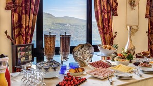 Un tavolo del buffet con diversi cibi e vista sulle montagne attraverso una finestra.