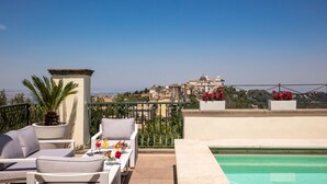 Una terrazza sul tetto con piscina, zona relax e vista su una cittadina storica.