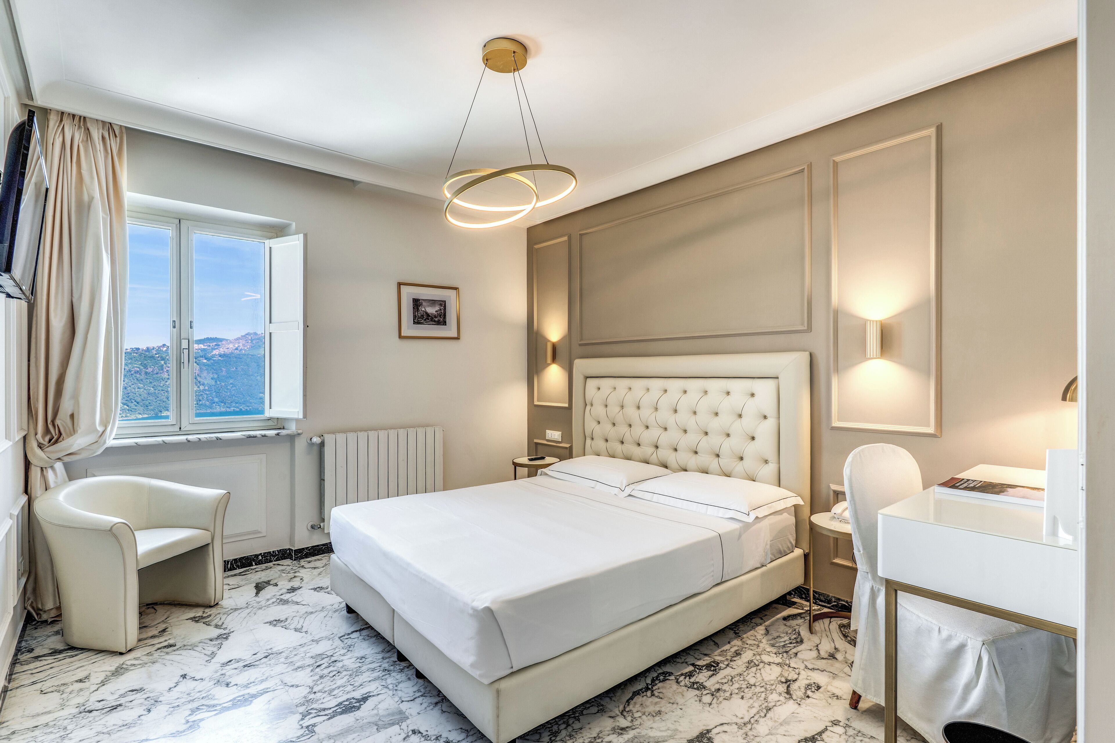 Habitación de hotel con una cama grande, un escritorio, una silla, una ventana con cortinas y vistas al exterior.