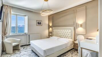 Habitación de hotel con una cama grande, un escritorio, una silla, una ventana con cortinas y vistas al exterior.