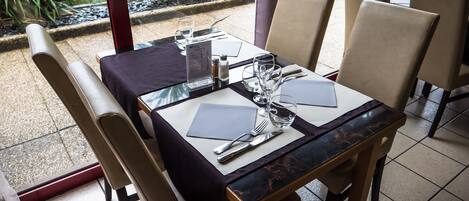 A table set for two with a menu, glasses, and cutlery.