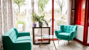 Une pièce moderne avec des fauteuils turquoise, une petite table et une plante en pot.