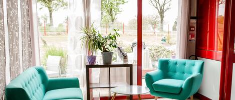 A modern room with teal armchairs, a small table, and a potted plant.
