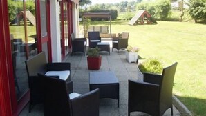 Une terrasse extérieure avec des meubles en osier, une petite table et des plantes en pot.