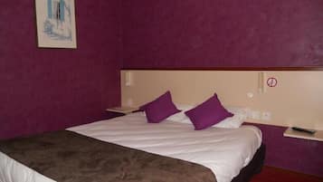 Ein Hotelzimmer mit einem großen Bett, violetten Kissen, einem Kopfteil und einem Bild an der Wand.