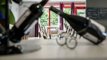 Un área de comedor con mesas y sillas, un menú en una pizarra y vistas a árboles a través de las ventanas.
