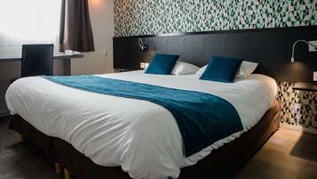 Een groot bed met een wit- en blauwe spreidekker, twee blauwe kussens en een donker hoofdbord.