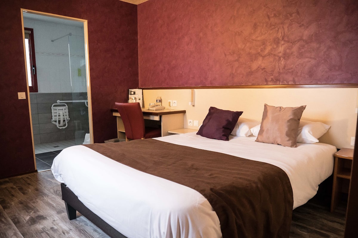 Una habitación de hotel con una cama grande, un escritorio y una silla.