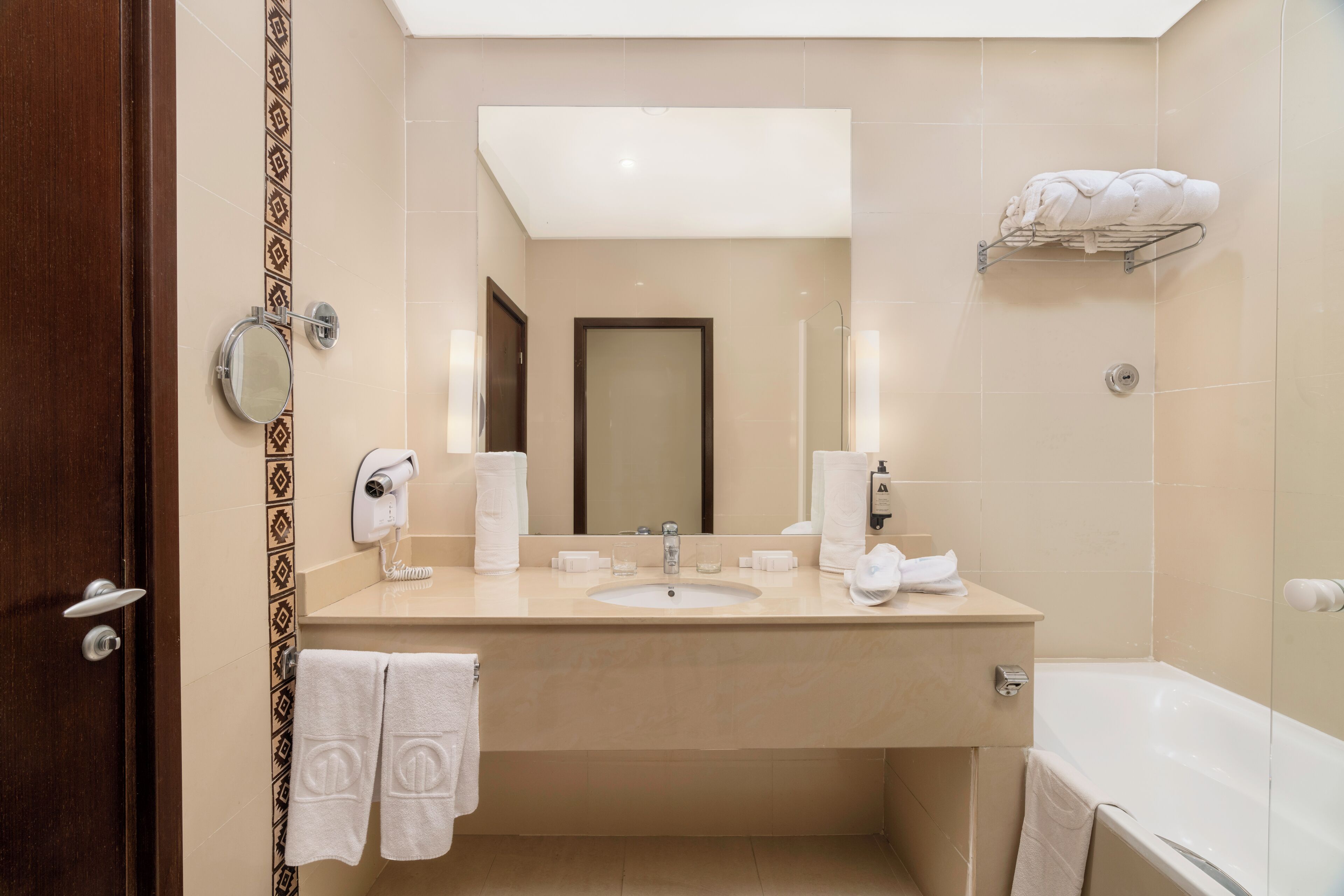 A modern bathroom with a sink, mirror, towel rack, and a shower area.