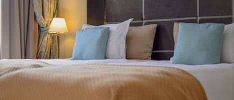 A hotel room with a large bed, a headboard with a grid pattern, and a lamp on a bedside table.