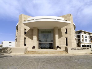 A modern building with a curved entrance, large glass windows, and a sign reading "ATLAS ESSAOUIRA & SPA".
