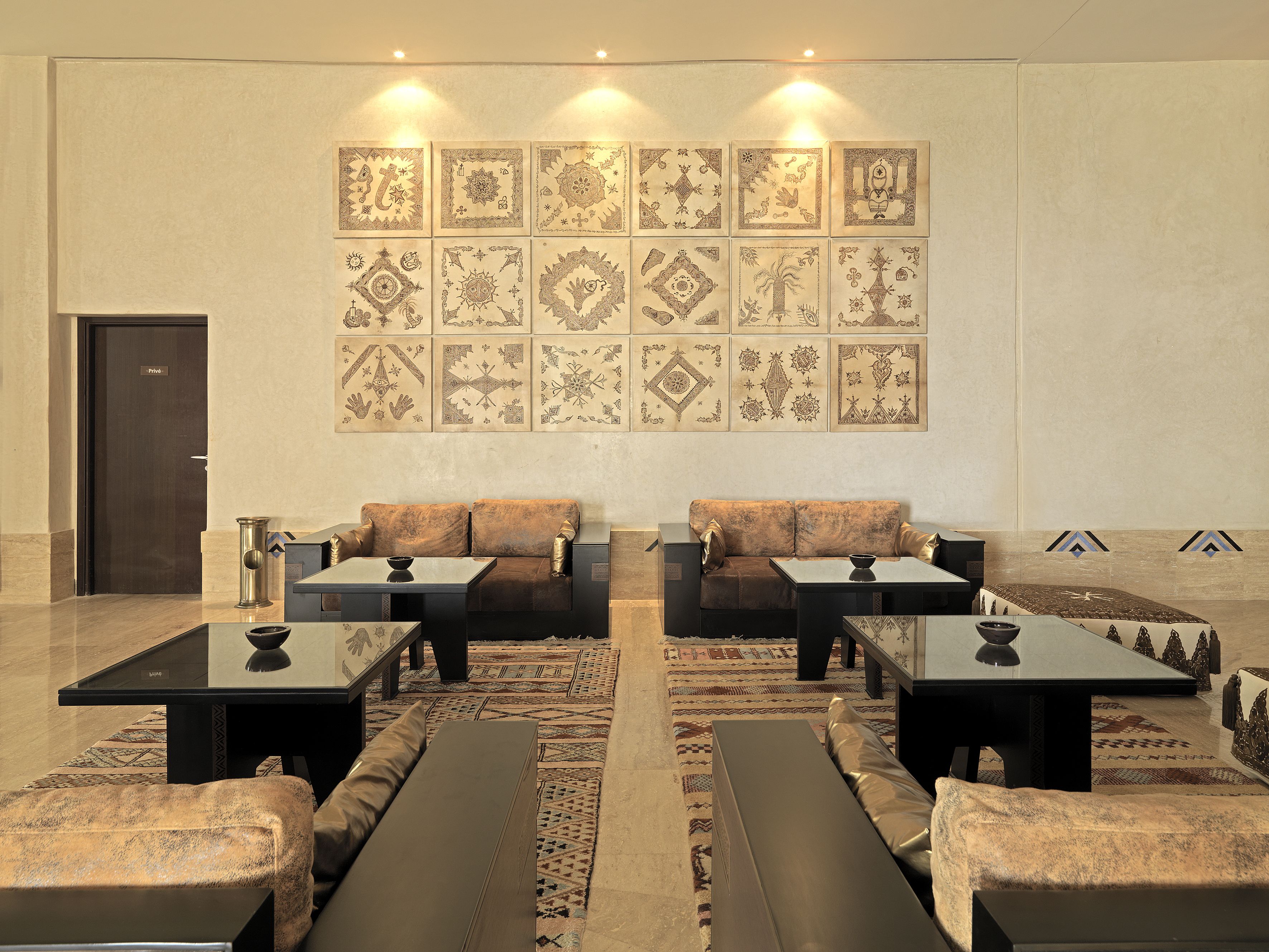 A spacious lobby with a modern design, featuring a large seating area with sofas and tables, a patterned wall, and a door labeled "Private".
