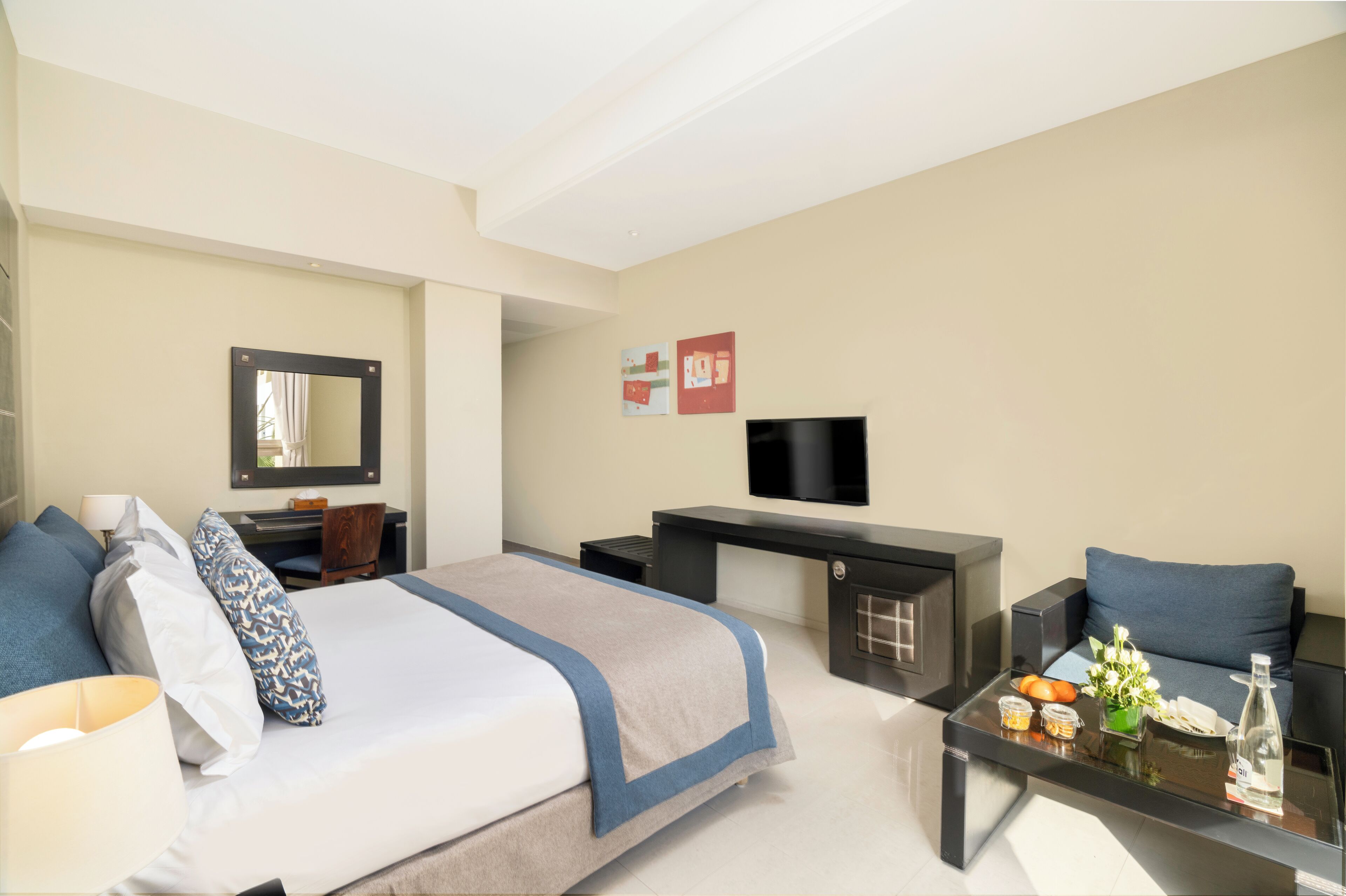 A modern hotel room with a bed, desk, and seating area.