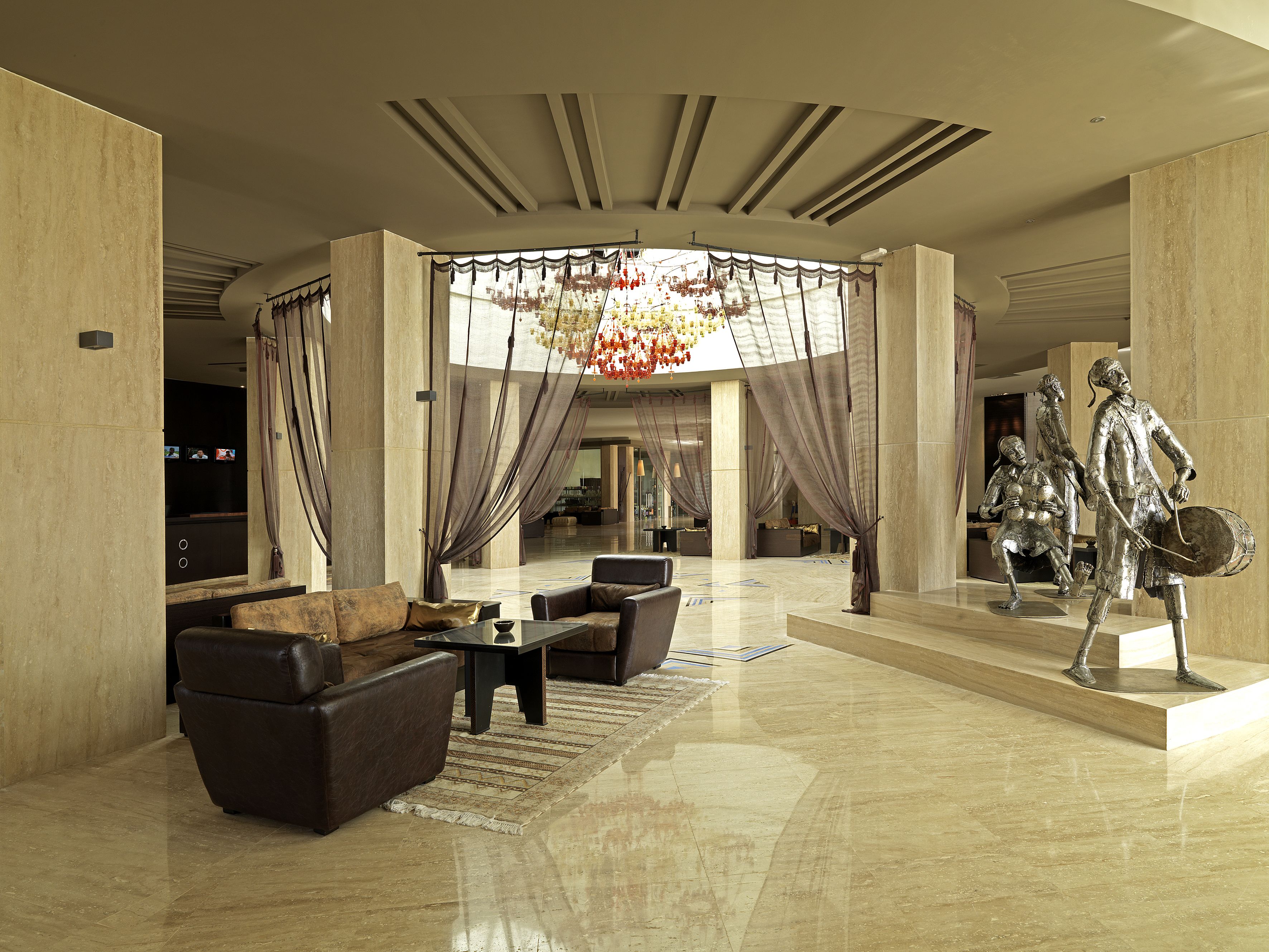 A spacious lobby with a high ceiling, a chandelier, and a statue of a historical figure.