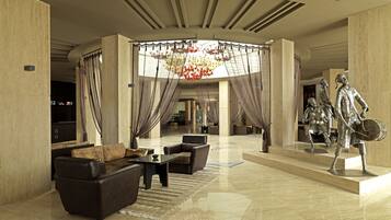 A spacious lobby with a high ceiling, a chandelier, and a statue of a historical figure.