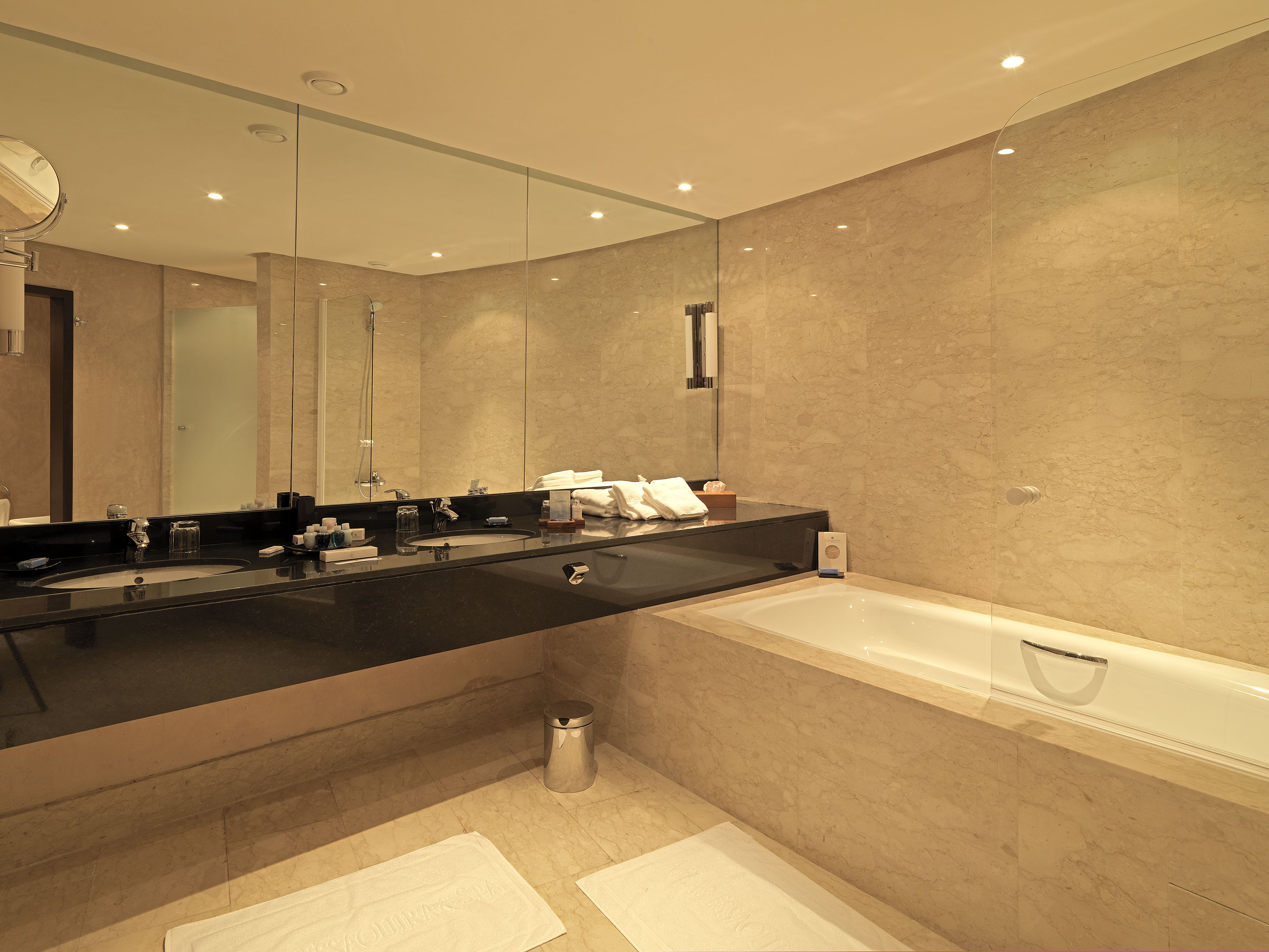 Un baño moderno con un espejo grande, lavamanos dobles y una bañera.